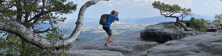 Fotograf balanciert auf geschwungenem Baumstamm im Elbsandsteingebirge-Lilienstein – Outdoor-Fotografie Großbritannien